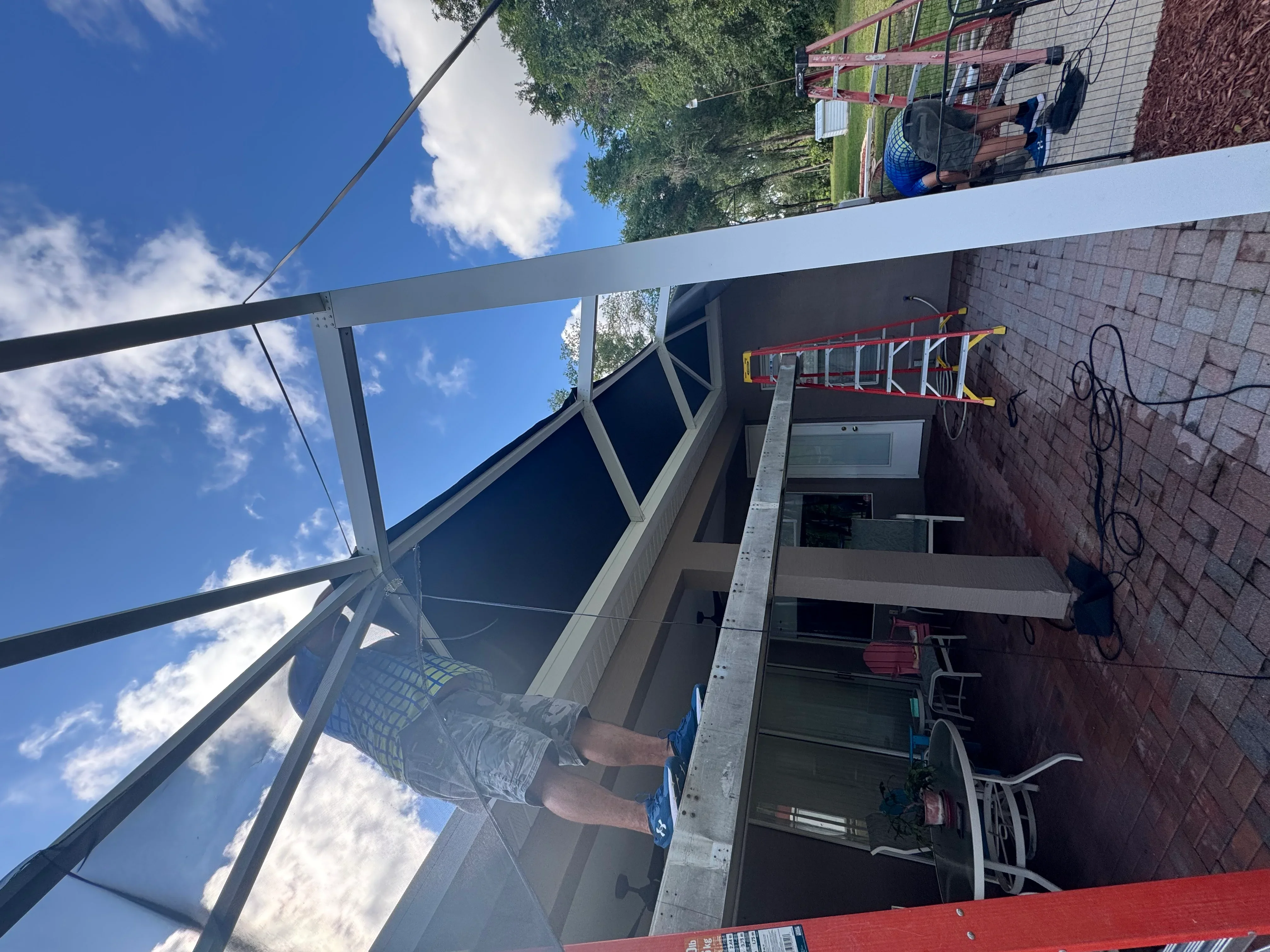 Aluminum frame screen enclosure with gray trim on brick residential addition during installation