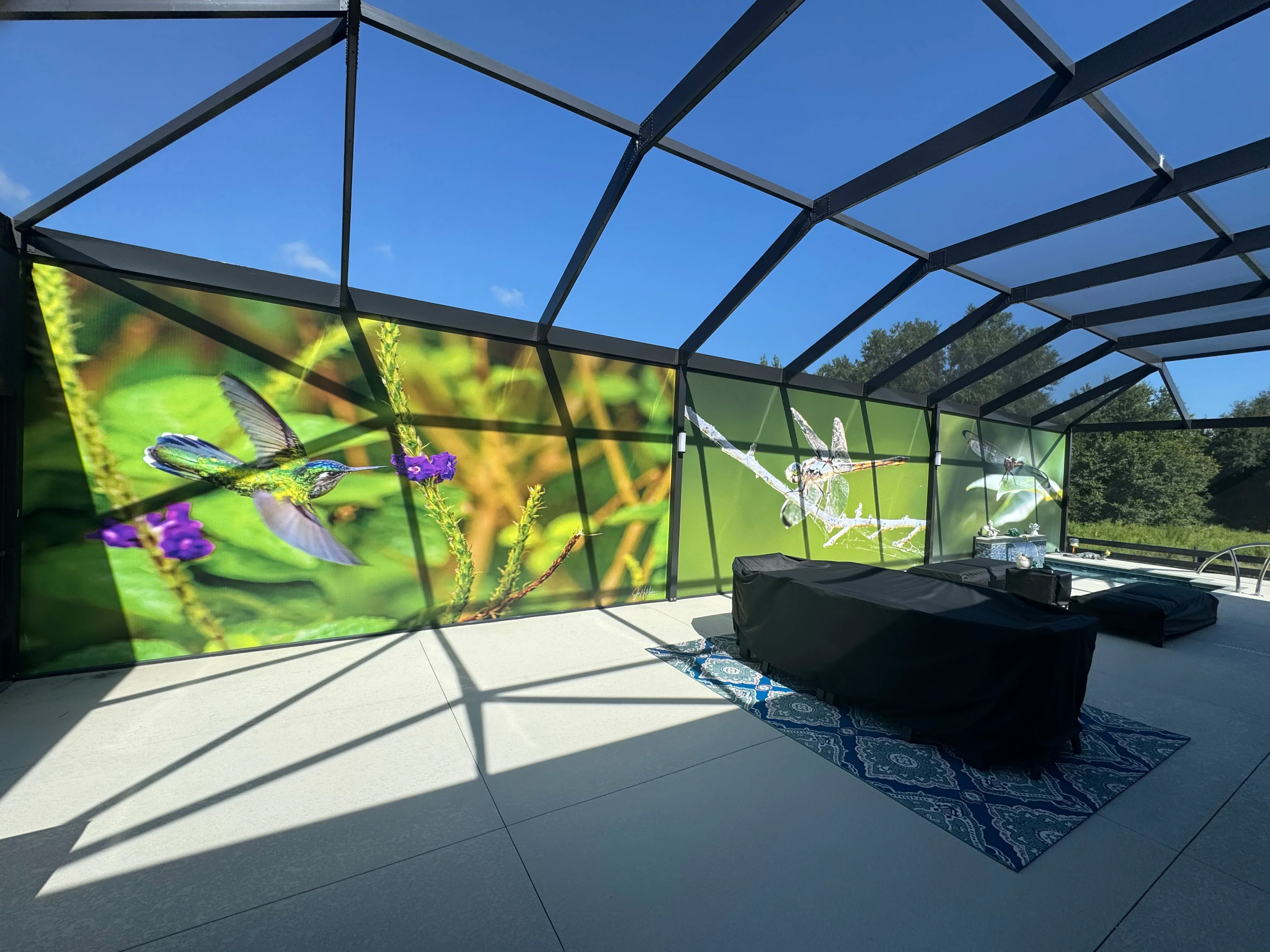 Aluminum screen enclosure with digital display panels showing dragonfly and nature imagery