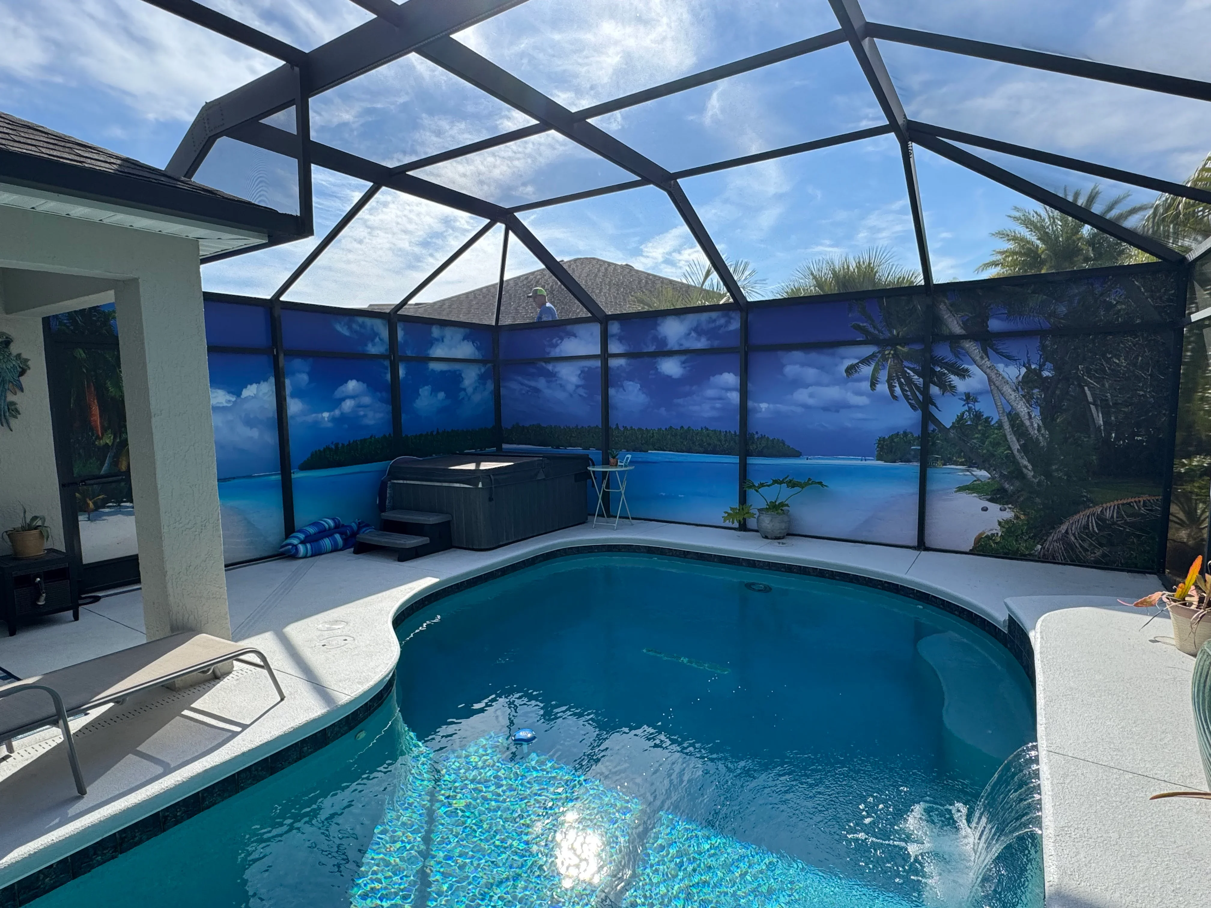 Black aluminum pool enclosure with glass roof panels and blue scenic screen panels surrounding turquoise pool