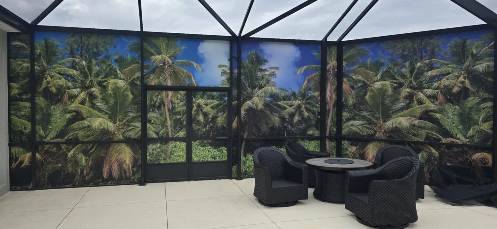 Black aluminum screen enclosure with tropical palm graphics, polycarbonate roof, and wicker seating