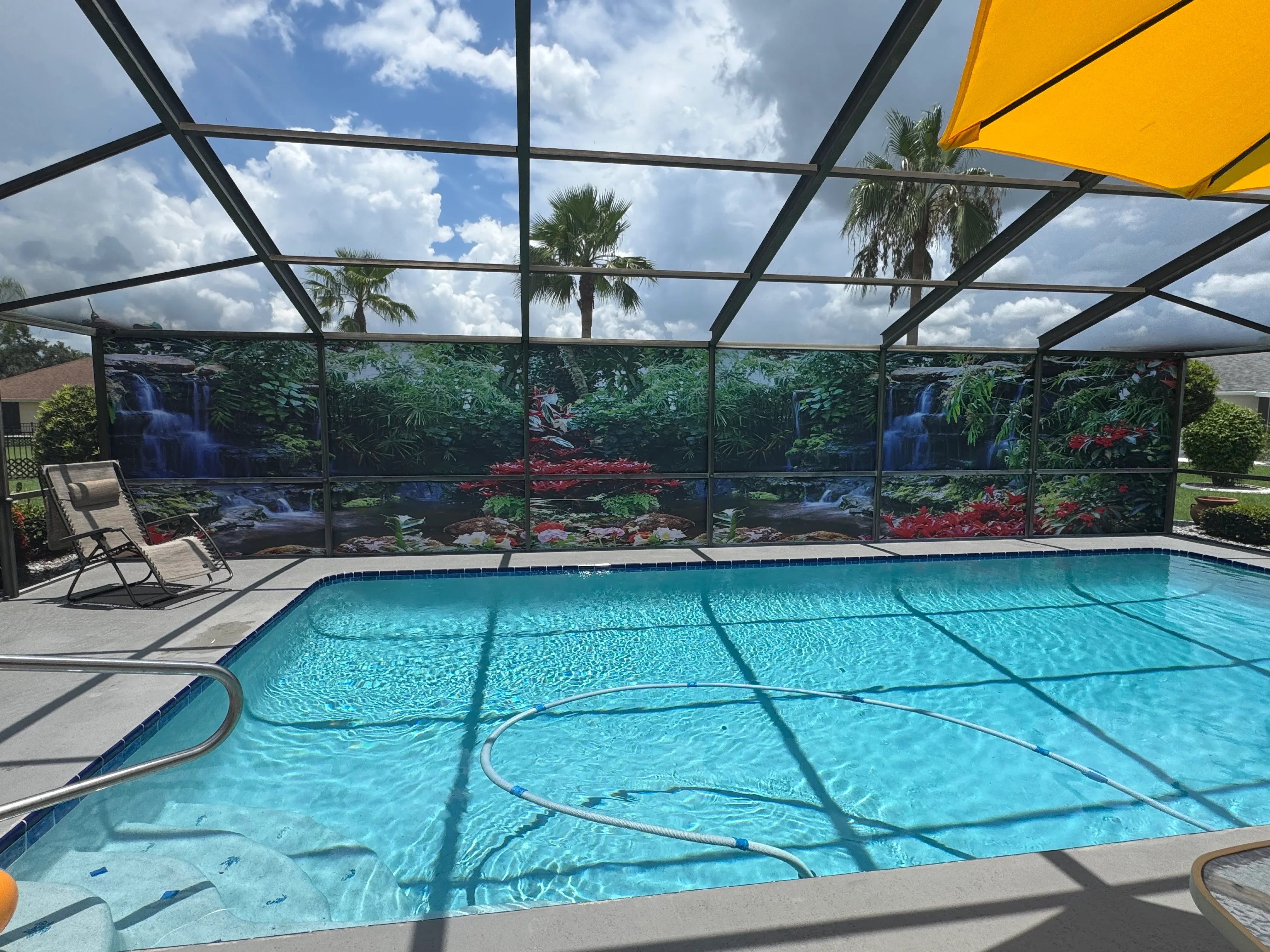 Pool enclosure with black frame, polycarbonate roof, and scenic waterfall panels