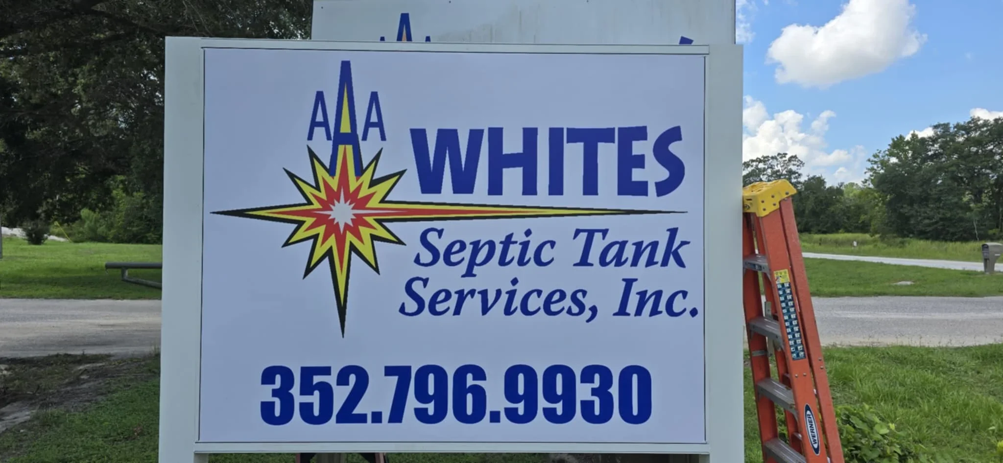Aluminum composite sign with blue and yellow graphics mounted on wooden post